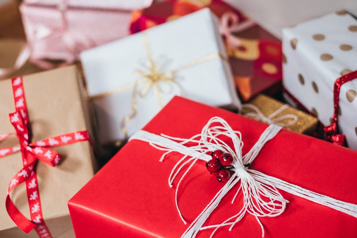 A pile of wrapped presents in red, white, and gold polka-dot paper, tied with ribbon and twine bows