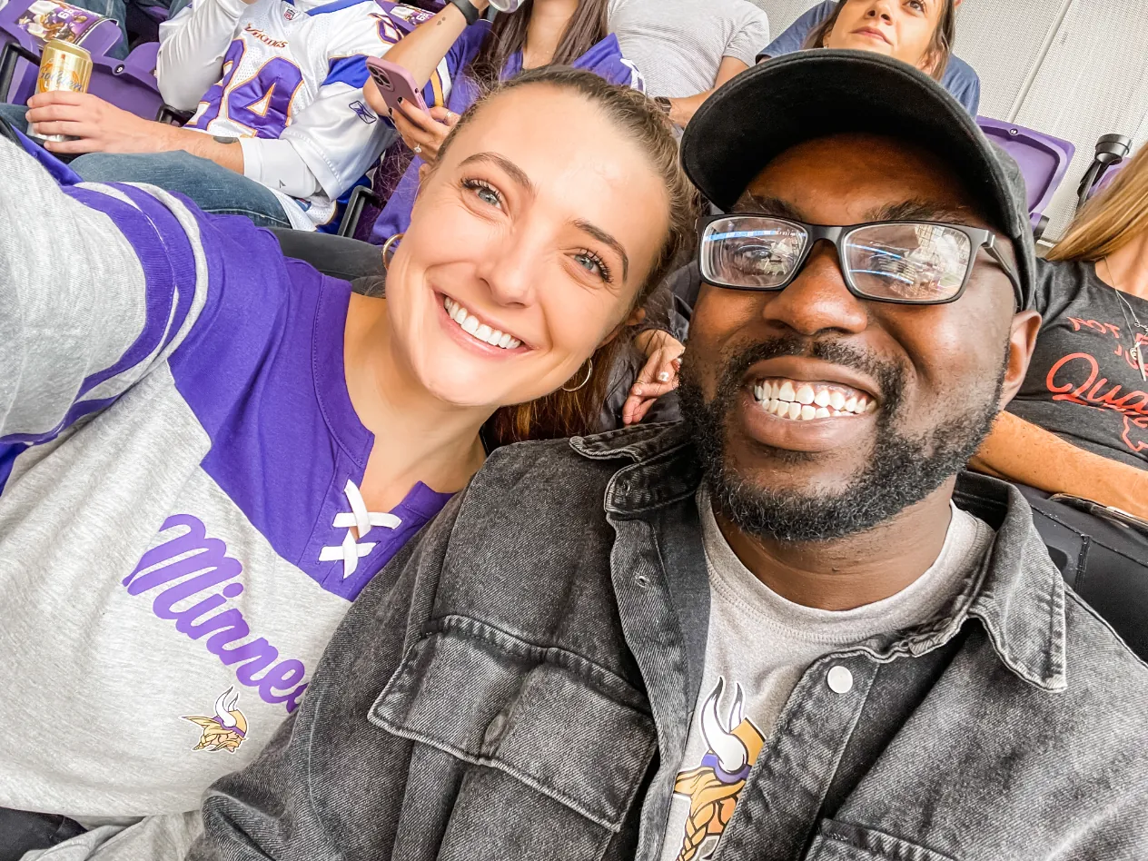 Two fans smiling in a selfie in the stands at a Minnesota Vikings game